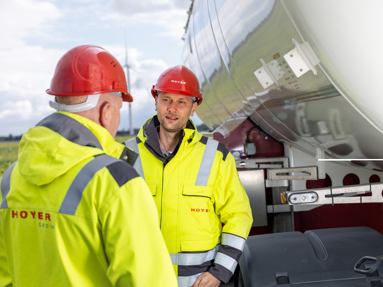 Vier HOYER Mitarbeiter knien neben HOYER Lkw Anschluessen 